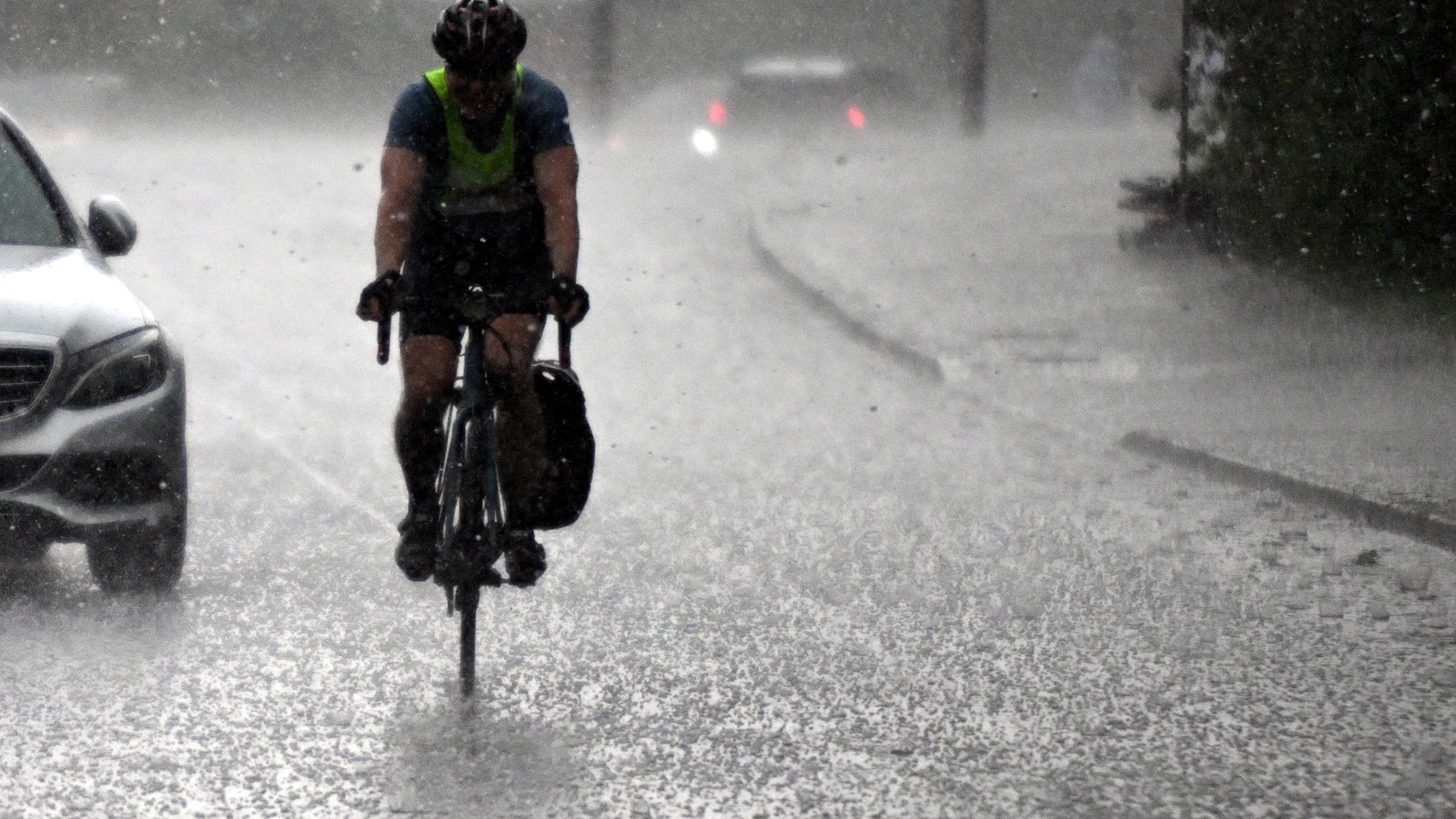 Nordrhein-Westfalen, Köln: Ein Radfahrer fährt durch einen Hagelschauer.