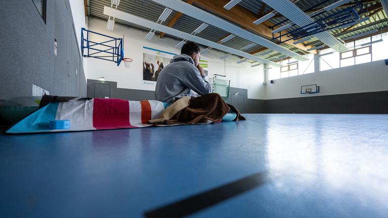 Symbolbild: Ein Student sitzt in einer Turnhalle auf einer Isomatte.  