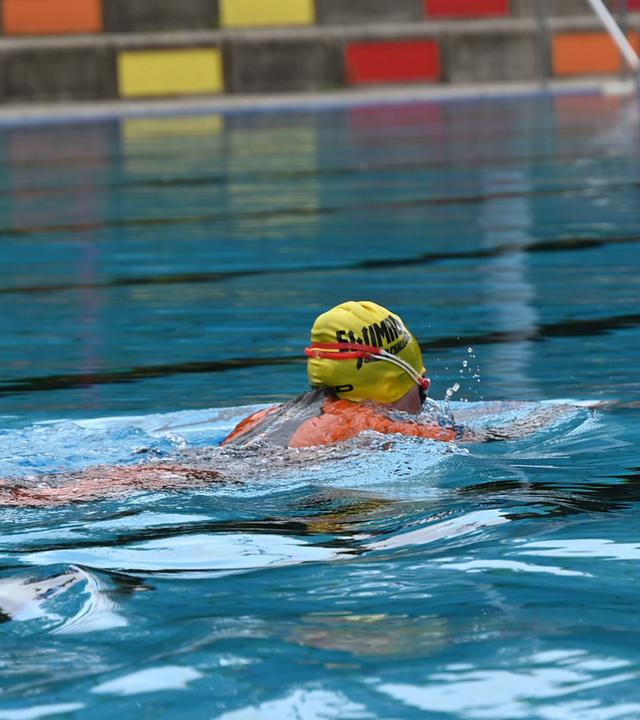 Eine Schwimmerin zieht in einem Schwimmbad ihre Bahnen.