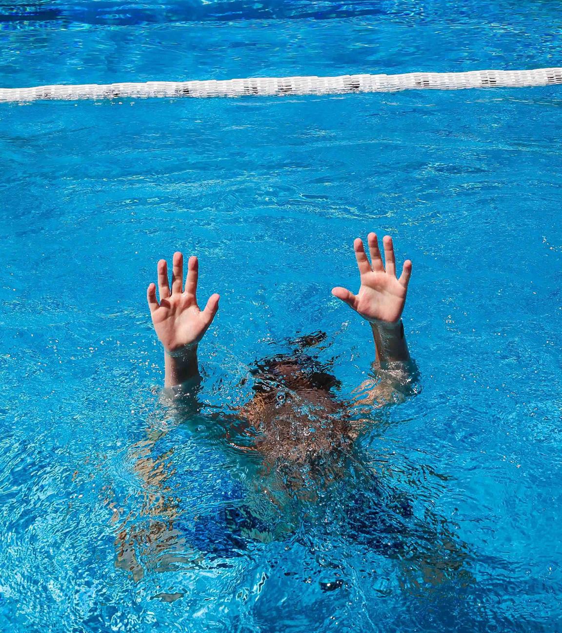 (Symbolbild) Ein Kind versucht im Schwimmbecken auf sich aufmerksam zu machen.