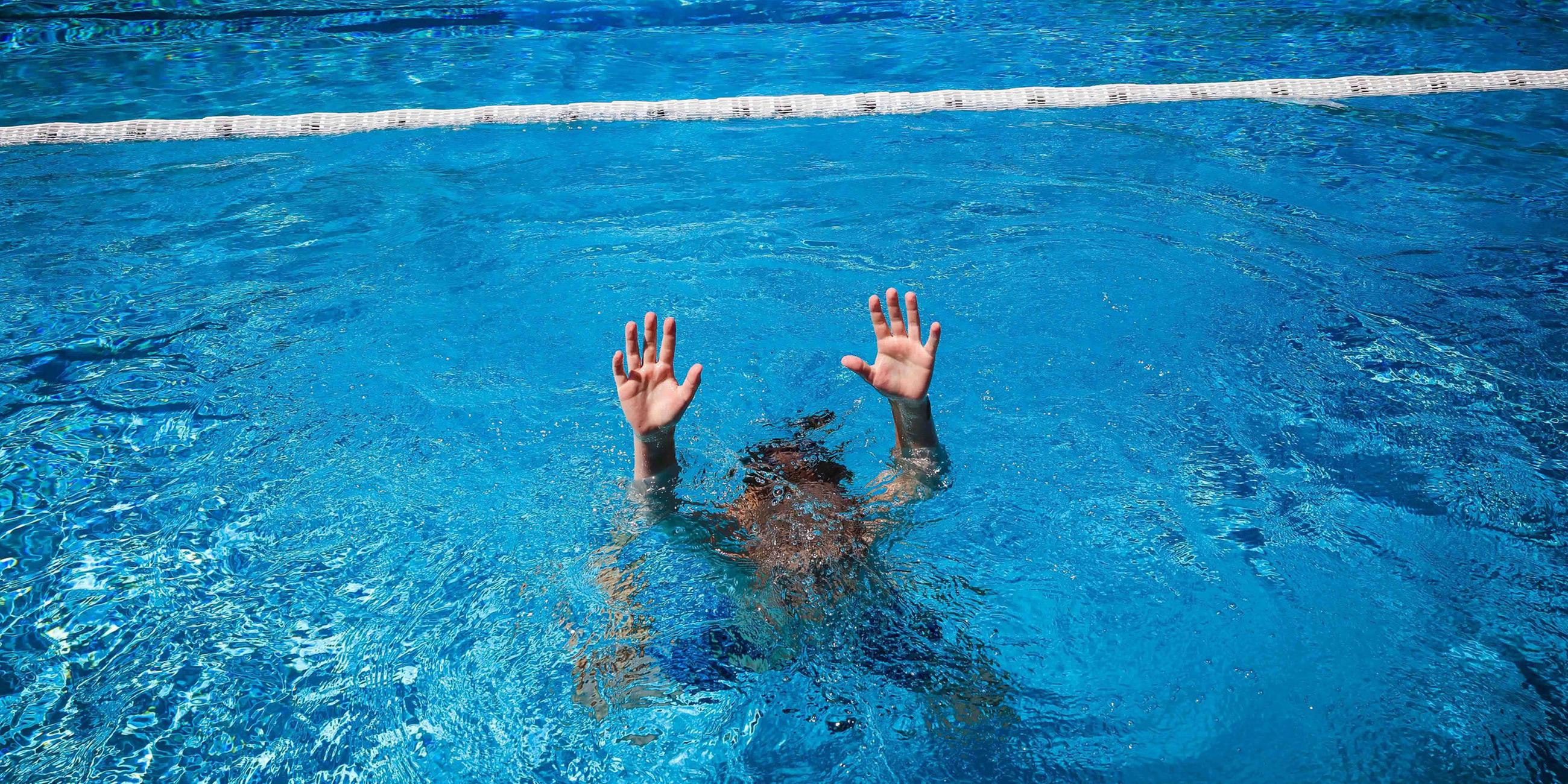 (Symbolbild) Ein Kind versucht im Schwimmbecken auf sich aufmerksam zu machen.