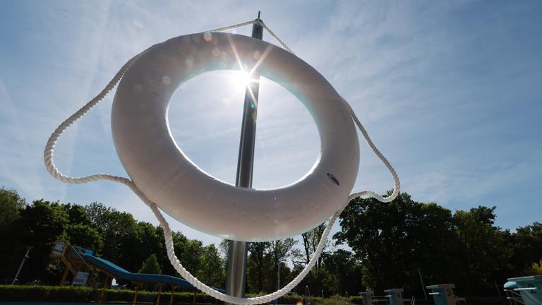 Sonne scheint durch Rettungsring, im Hintergrund Becken.