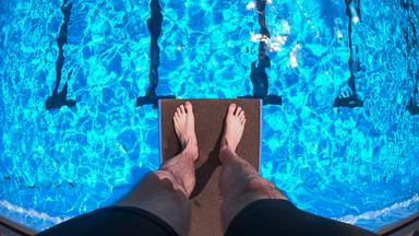 Nordrhein-Westfalen, Detmold: Ein Schwimmer steht auf einem Sprungbrett über dem Becken im Freibad Hiddesen.