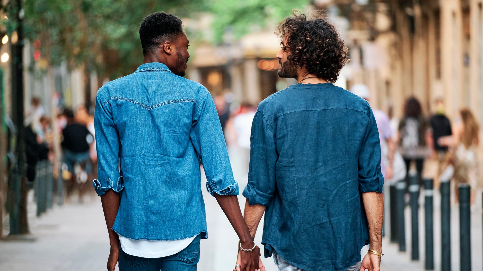 Zwei Männer gehen Händchen haltend durch Stadt