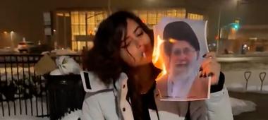 Eine junge Frau zündet ihre Zigarette an einem brennenden Porträt des Obersten Führers des Iran an, Ajatollah Ali Chamenei. 