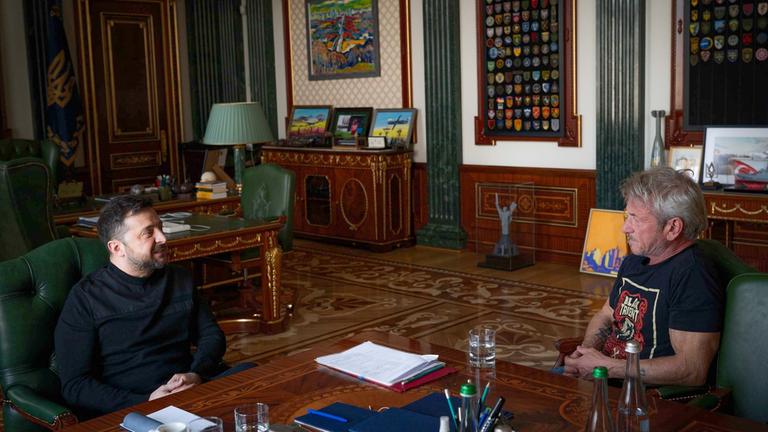 Sean Penn und Wolodymyr Selenskyj sitzen in einem Büro und reden miteinander.