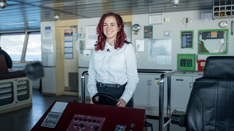 Selina Schwarz, Azubi auf dem Frachtschiff, steht am Steuerrad.