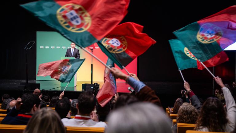 Der portugiesische Präsidentschaftskandidat António José Seguro steht auf einer Bühne, vor ihm werden große Fahnen seiner Partei geschwenkt.