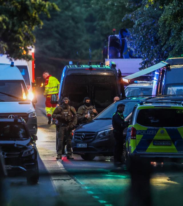 Auf einer Straße stehen mehrere Polizweiwagen und andere Einsatzwagen, es sind bewaffnete Einsatzkräfte des SEK zu sehen, mehrere Polizisten und ein Rettungssanitäter