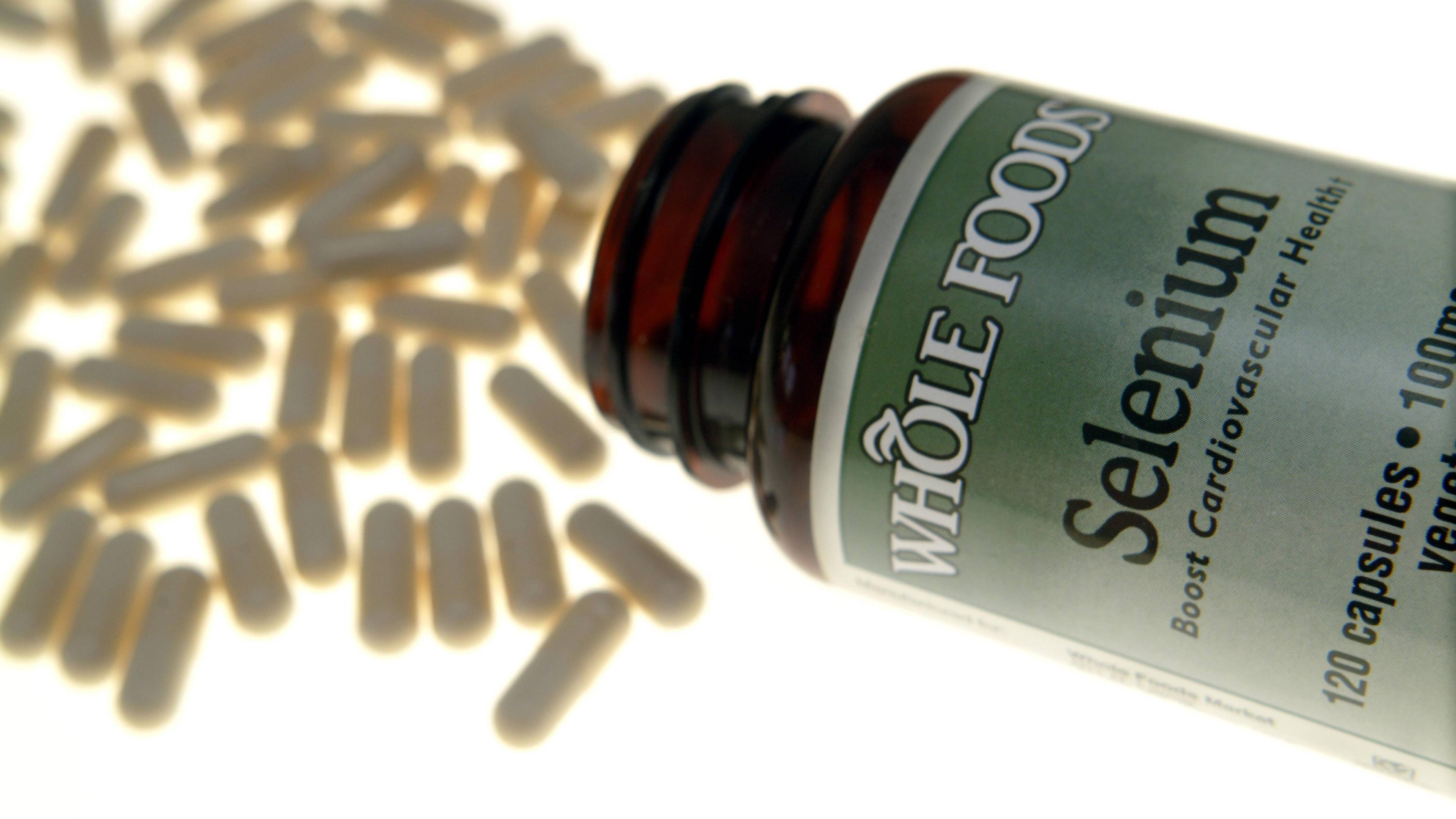 Selen-Tabletten liegen vor einer Medikamenten-Flasche.