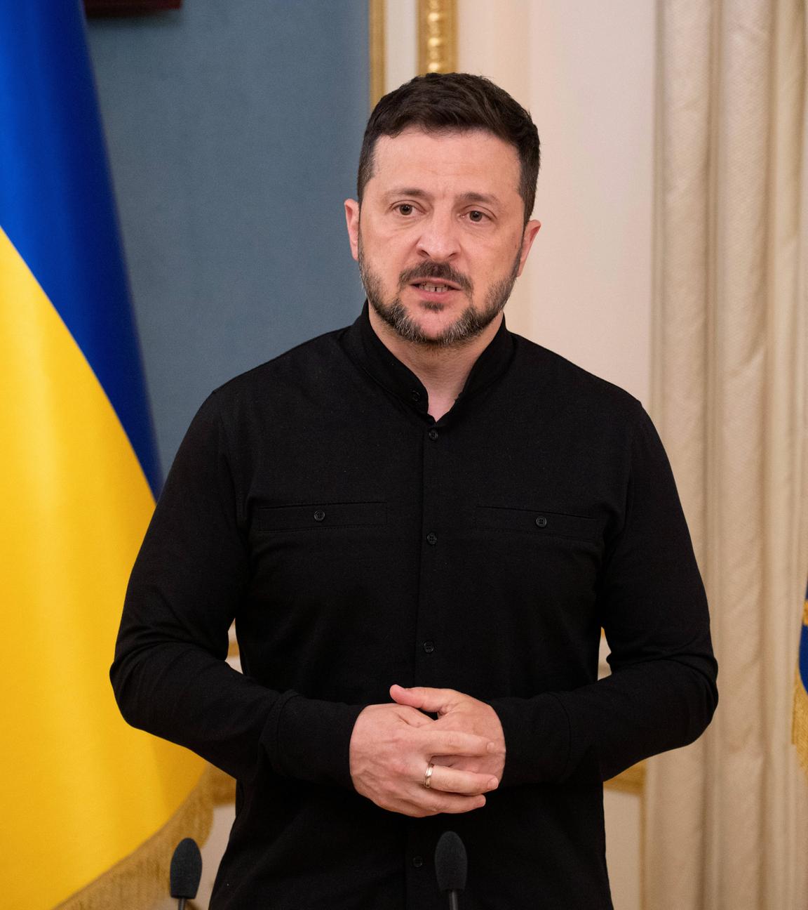 Selenskyj steht bei einem Briefing in Kiew vor einer Ukraine-Flagge.