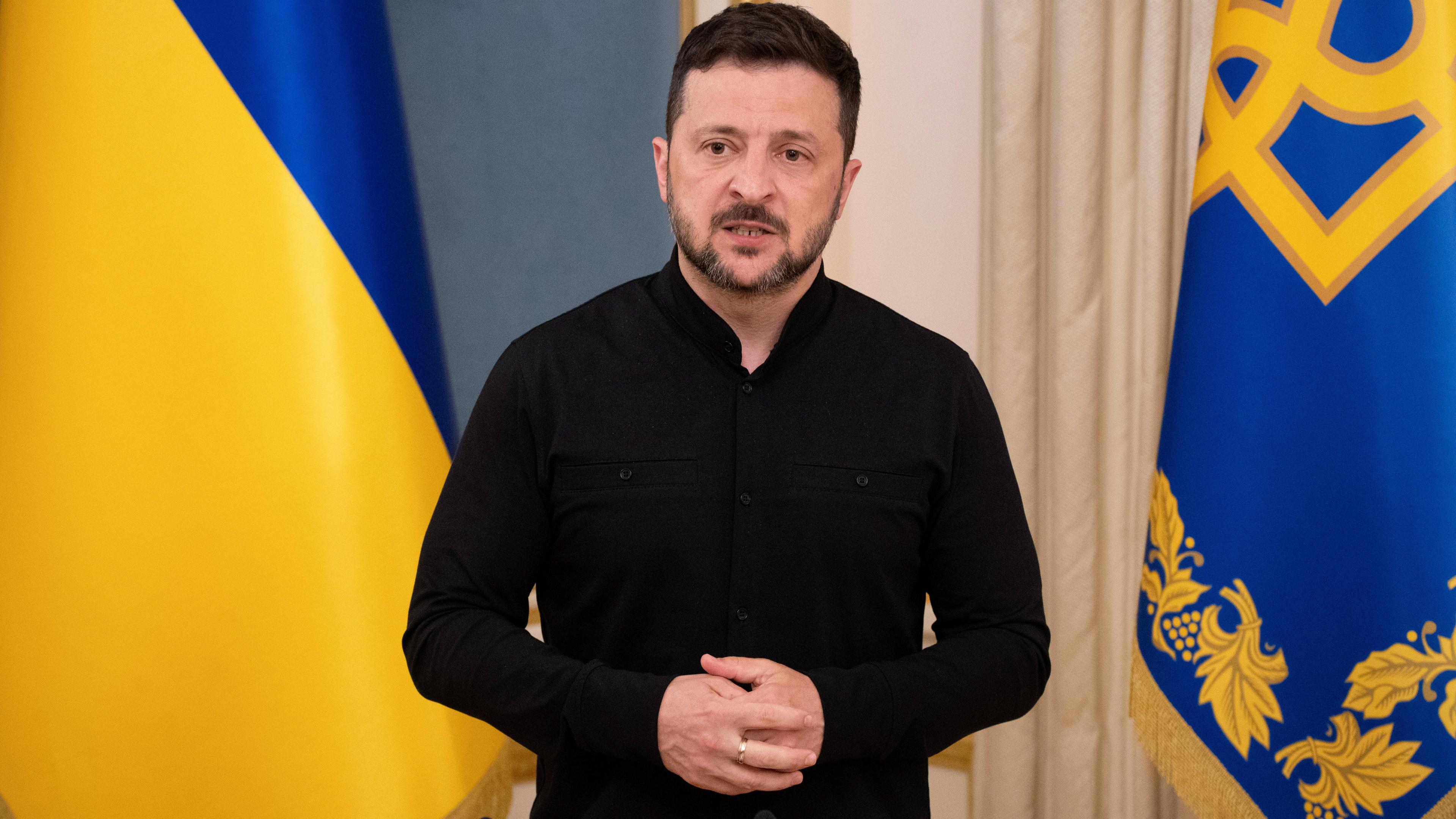 Selenskyj steht bei einem Briefing in Kiew vor einer Ukraine-Flagge.