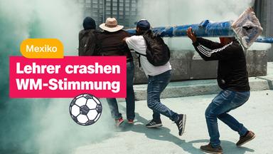 Menschen von hinten fotografiert tragen eine lange, schwere, blaue Stange, drumherum ist Qualm. Darüber eine Textbox "Lehrer crashen WM-Stimmung" und eine zusätzliche "Mexiko". Außerdem ein gezeichneter Fußball