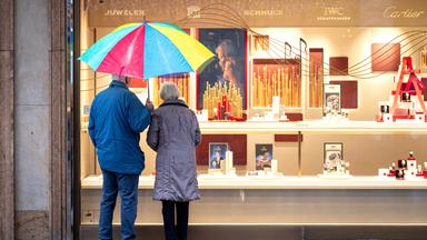 Zwei ältere Personen stehen am 02.12.2025 bei Regen vor einem Schaufenster eines Schmuckgeschäfts in Bremen und betrachten die ausgestellten Waren. 