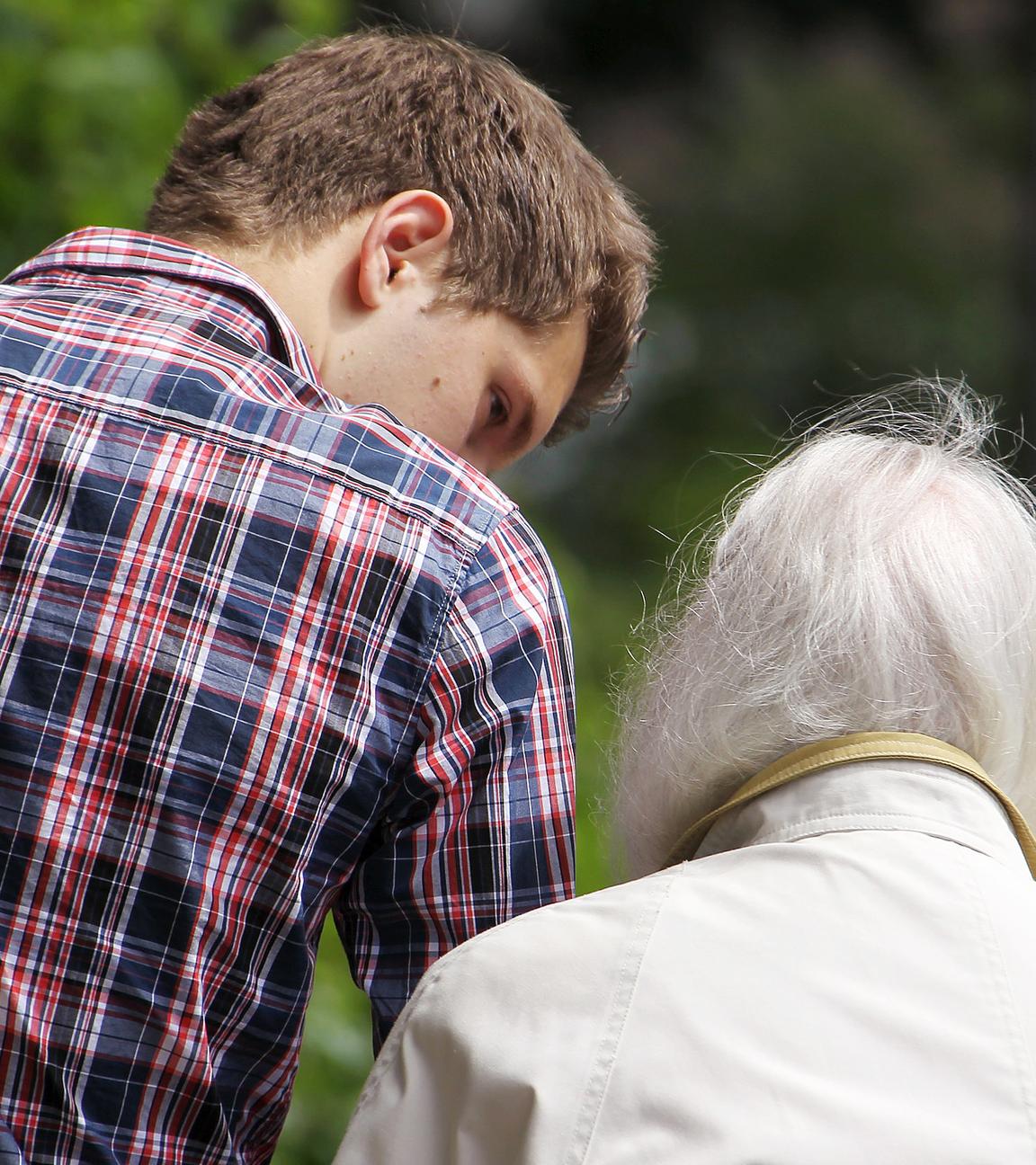 Ein junger Mann begleitet eine alte Frau  (Archivfoto)