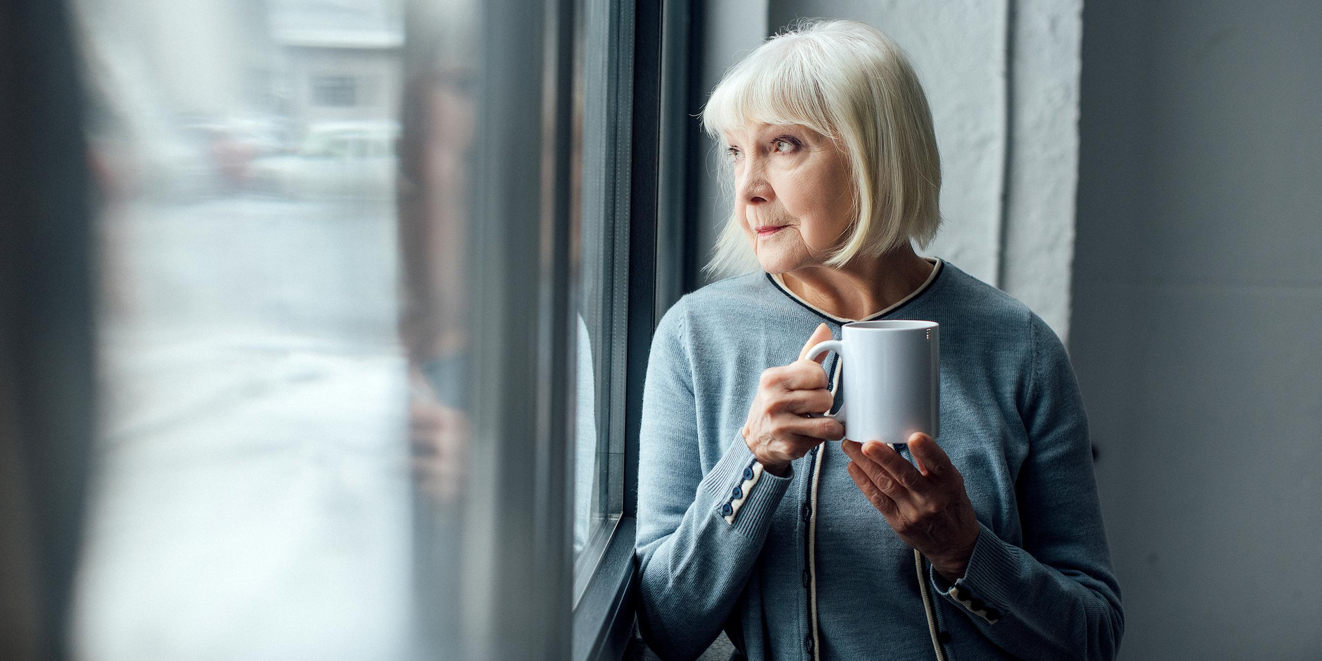 Seniorin mit Kaffee am Fenster