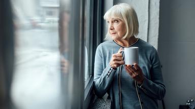 Seniorin mit Kaffee am Fenster