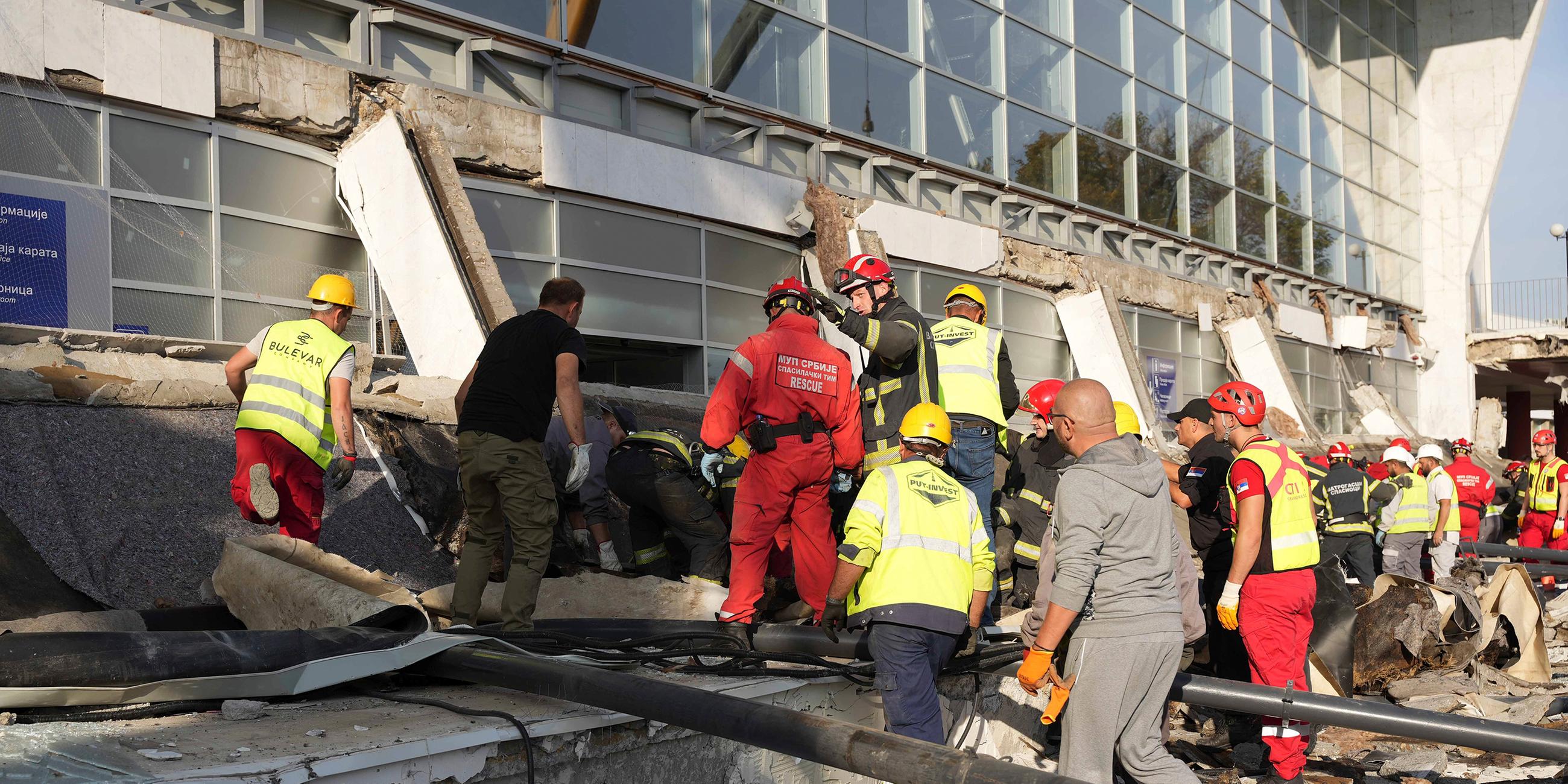 Mitarbeiter von Rettungsdiensten inspizieren das eingestürzte Dach eines Bahnhofs in Novi Sad