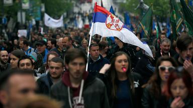 Demonstranten tragen eine serbische Flagge.