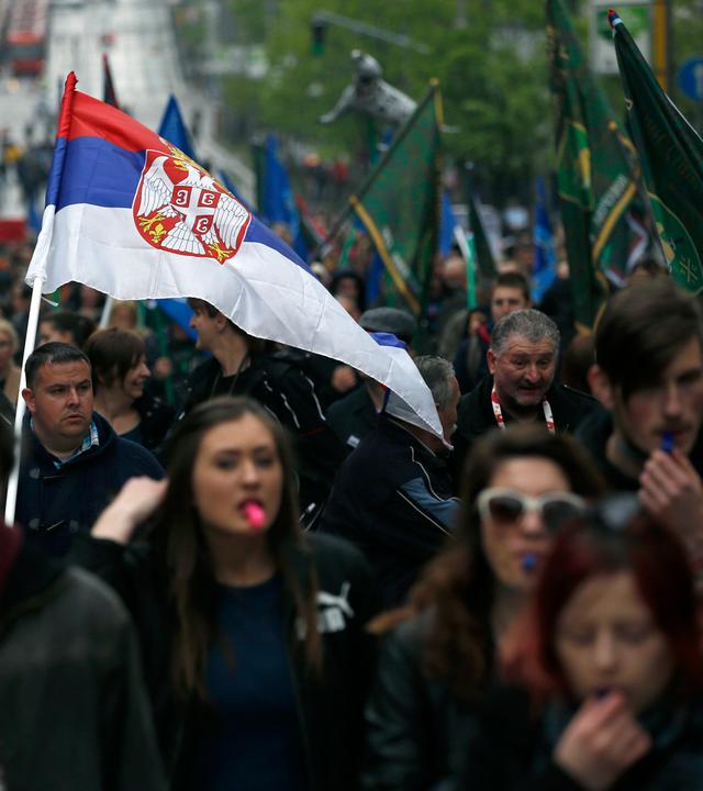 Demonstranten tragen eine serbische Flagge.