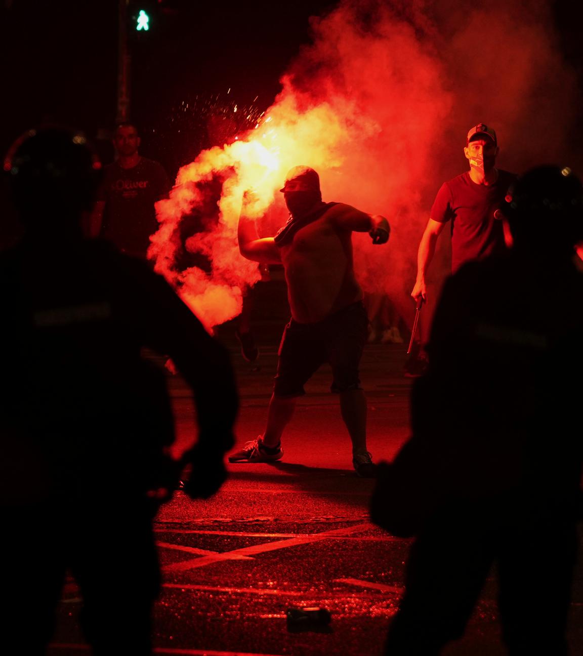 14.08.2025, Serbien, Belgrad: Anhänger des serbischen Präsidenten Vucic werfen während einer Demonstration gegen die Regierung vor dem Büro der serbischen Fortschrittspartei Leuchtraketen auf die Demonstranten.