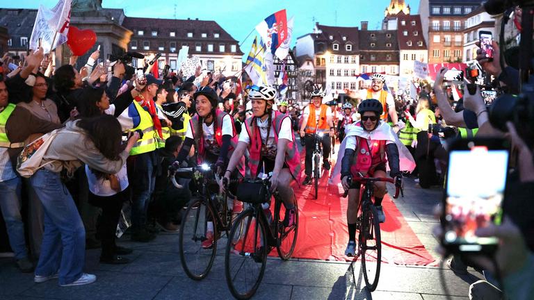 Serbische Studenten erreichen mit dem Fahrrad den Place Kléber und beenden damit am 15. April 2025 ihre Radtour von Novi Sad nach Straßburg in Ostfrankreich. 