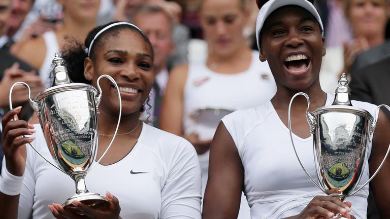 Serena und Venus Williams posieren nach ihrem Wimbledon-Sieg 2016 mit Pokalen