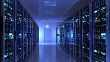 Der Serverraum eines Rechenzentrums ist zu sehen, der Gang leuchtet blau. An der Wand links und rechts stehen die ebenfalls leuchtenden Server.