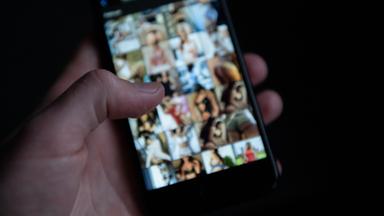 Hand mit Smartphone. Unscharf auf dem Display: pornografisches Material.