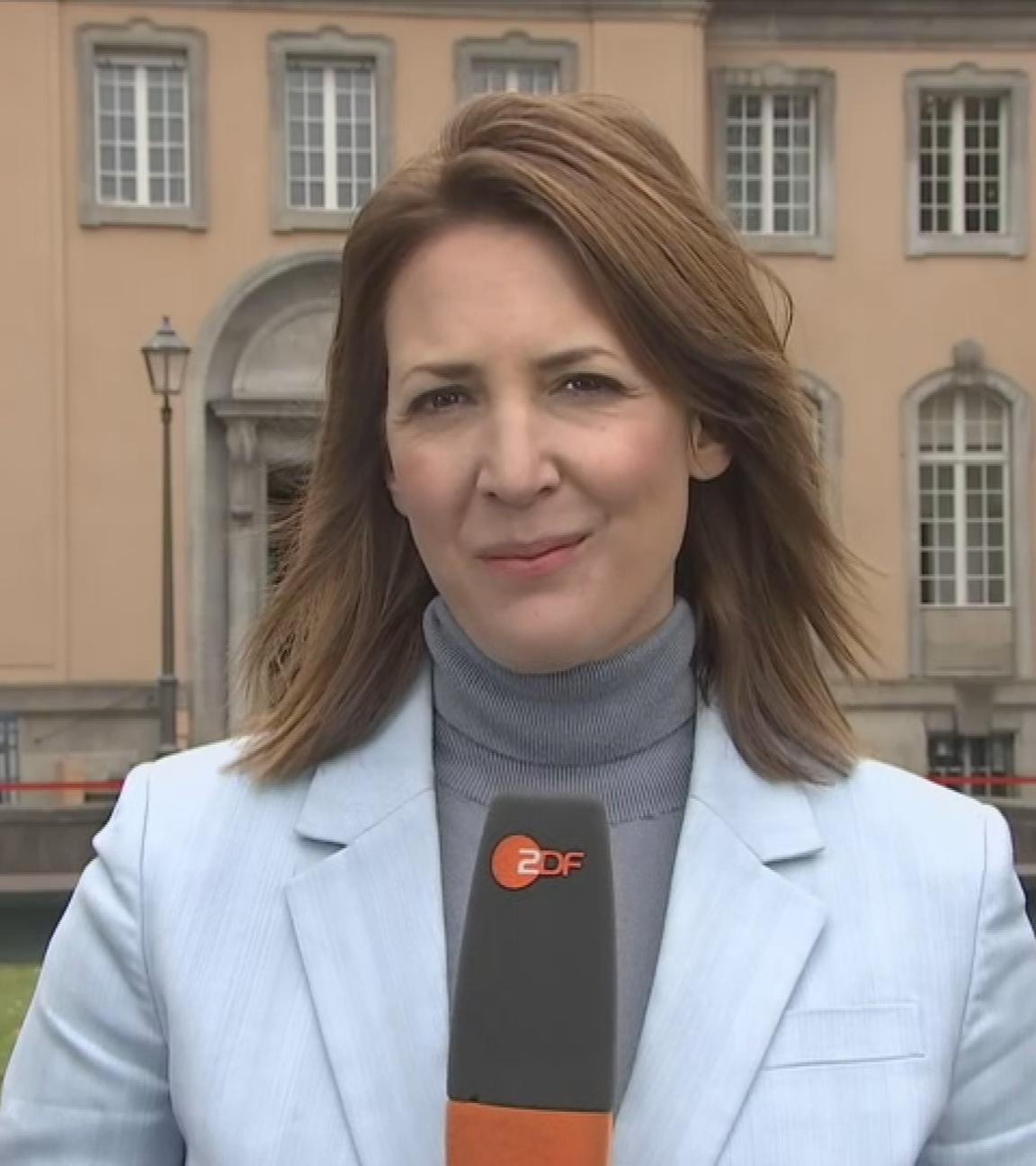 Es ist die Reporterin Andrea Maurer zu sehen, wie sie mit einem Mikrofon in der Hand über die Kabinettsklausur spricht
