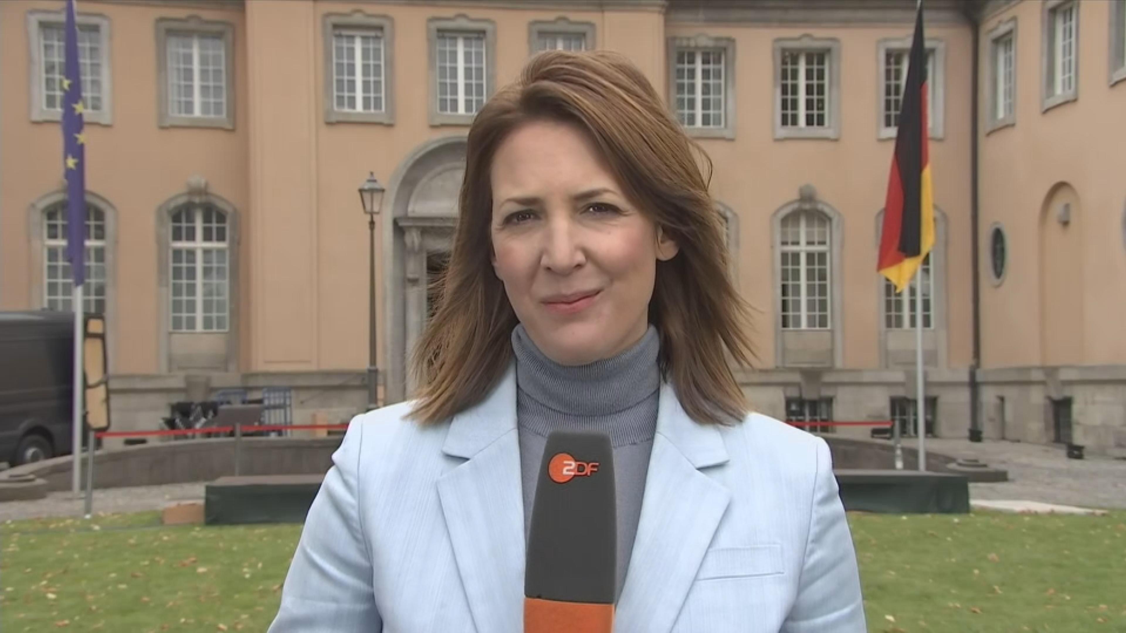 Es ist die Reporterin Andrea Maurer zu sehen, wie sie mit einem Mikrofon in der Hand über die Kabinettsklausur spricht