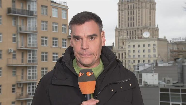 ZDF-Korrespondent Coerper mit einem Mikrofon in der Hand.