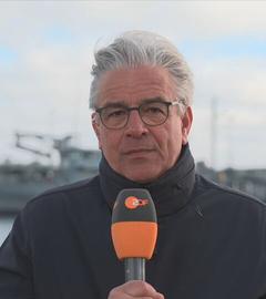ZDF-Korrespondent Hebestreit ist zu sehen, während im Hintergrund Schiffe zu sehen sind.