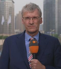 ZDF-Korrespondent Elmar Theveßen ist mit einem Mikrofon in der Hand in Peking zu sehen.