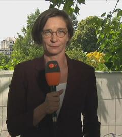 ZDF-Korrespondentin Zimmermann ist mit einem Mikrofon in der Hand in Evian, Frankreich zu sehen.