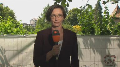 ZDF-Korrespondentin Zimmermann ist mit einem Mikrofon in der Hand in Evian, Frankreich zu sehen.