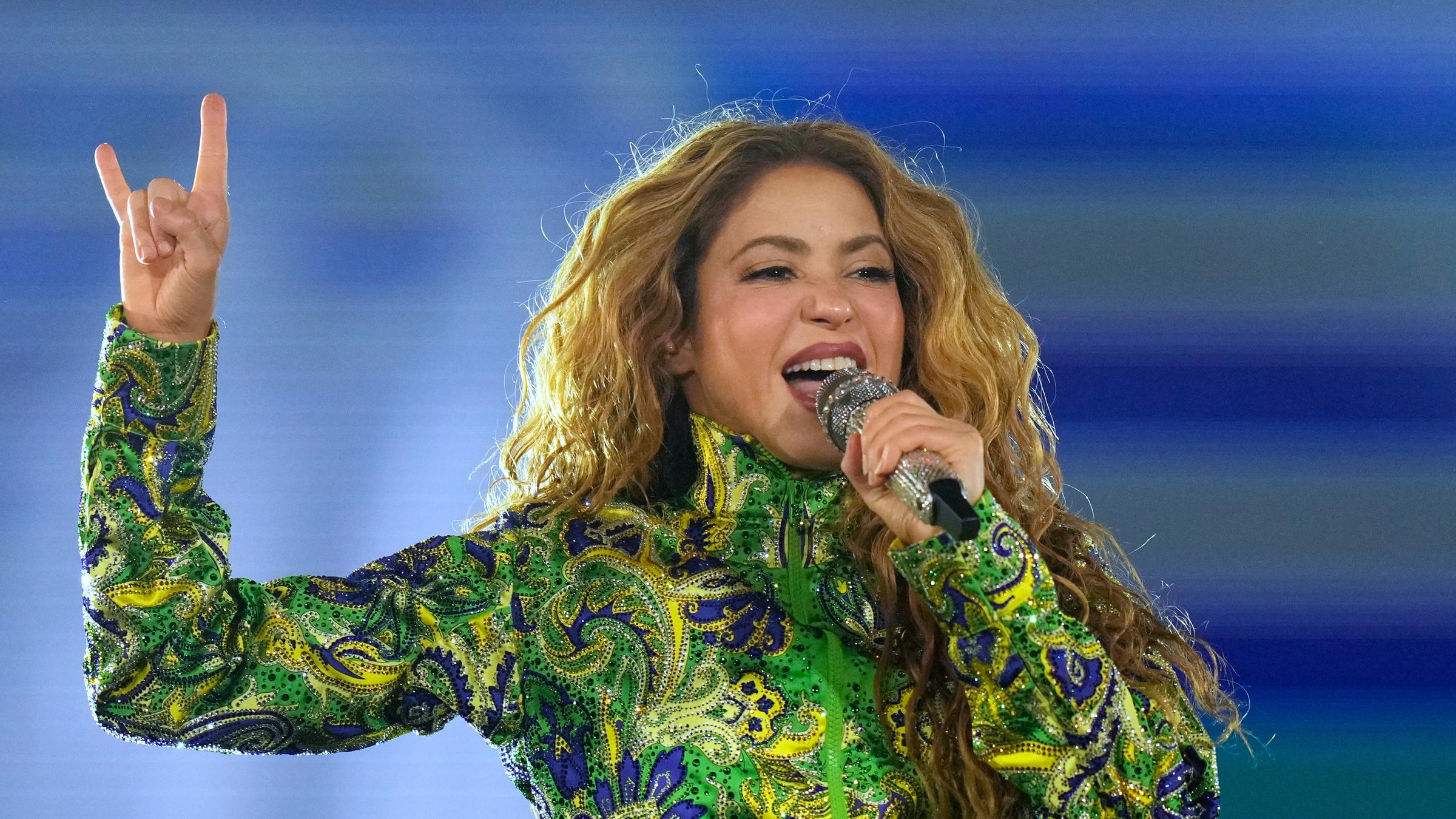 Sängerin Shakira performt in einer Jacke in den Nationalfarben Brasiliens - grün und gelb - auf der Bühne.