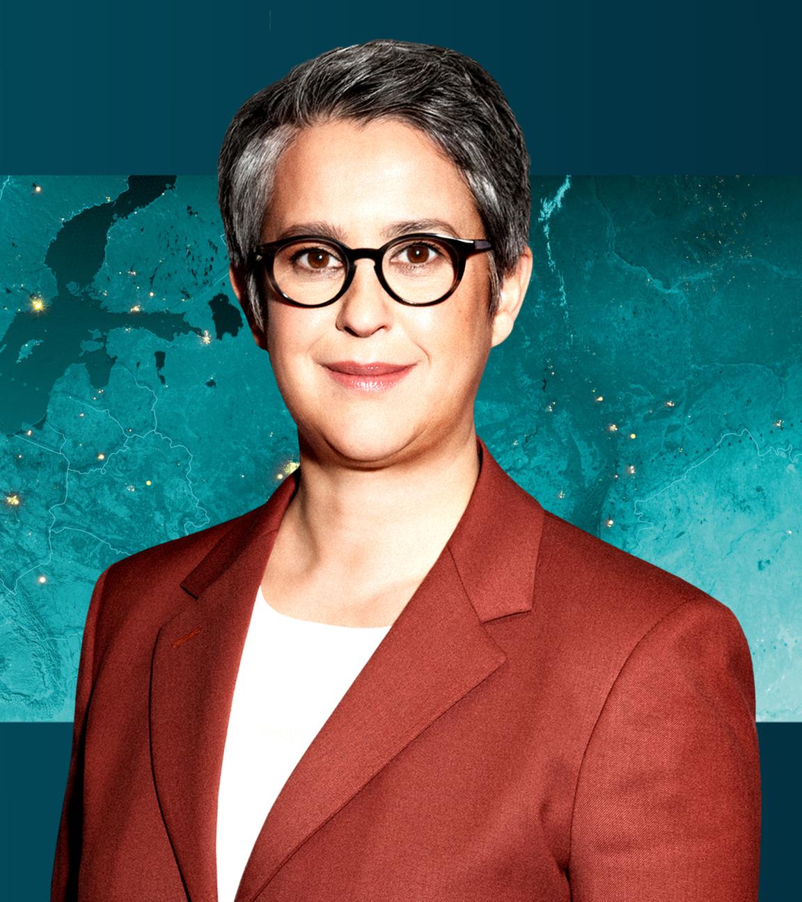 Shakuntala Banerjee vor einer Weltkarte.
