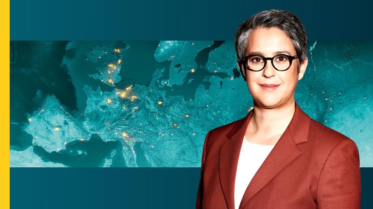 Shakuntala Banerjee vor einer Weltkarte.