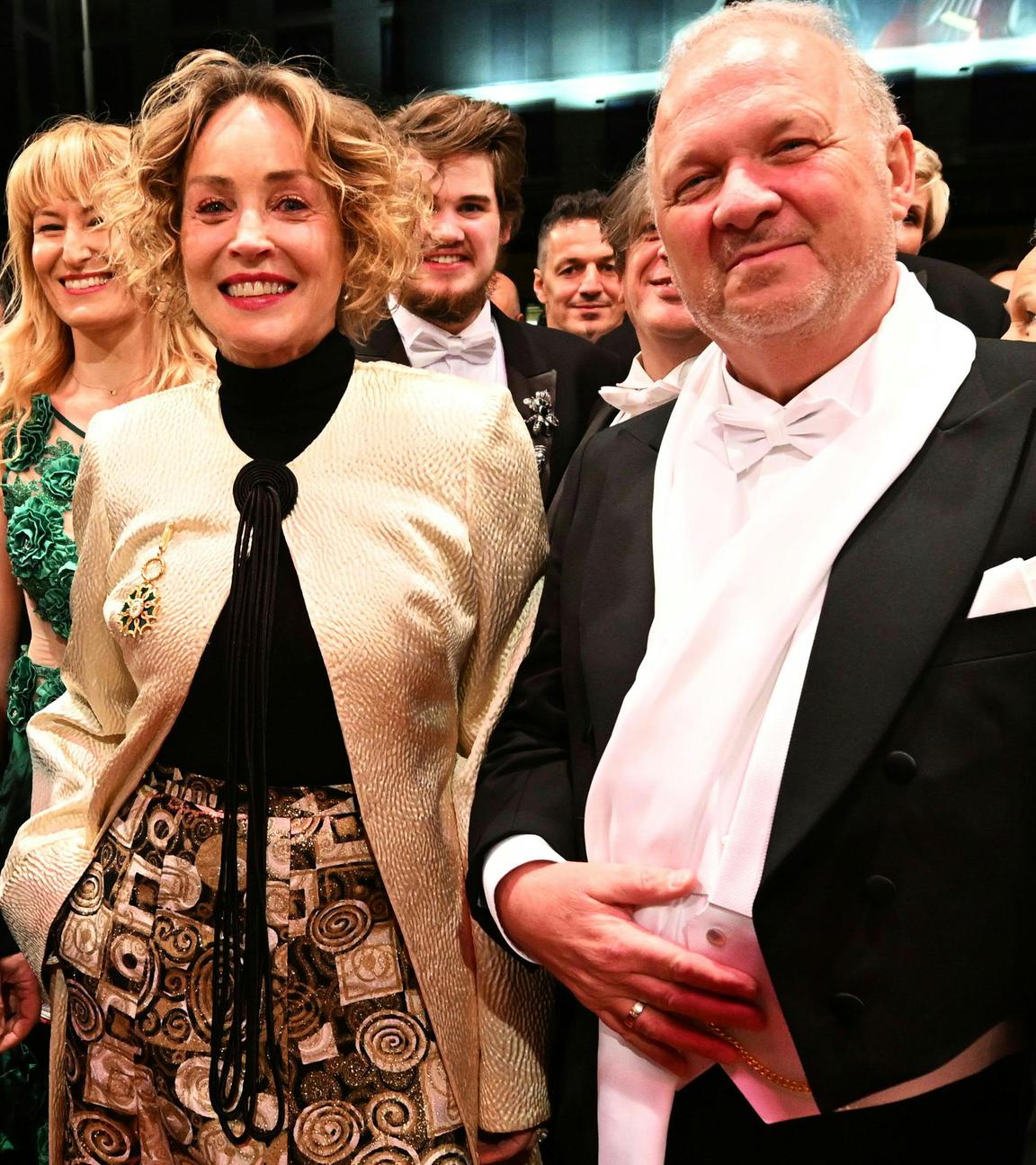 Sharon Stone ist zu sehen, wie sie auf dem Wiener Opernball mit mehreren Menschen ein Foto macht.
