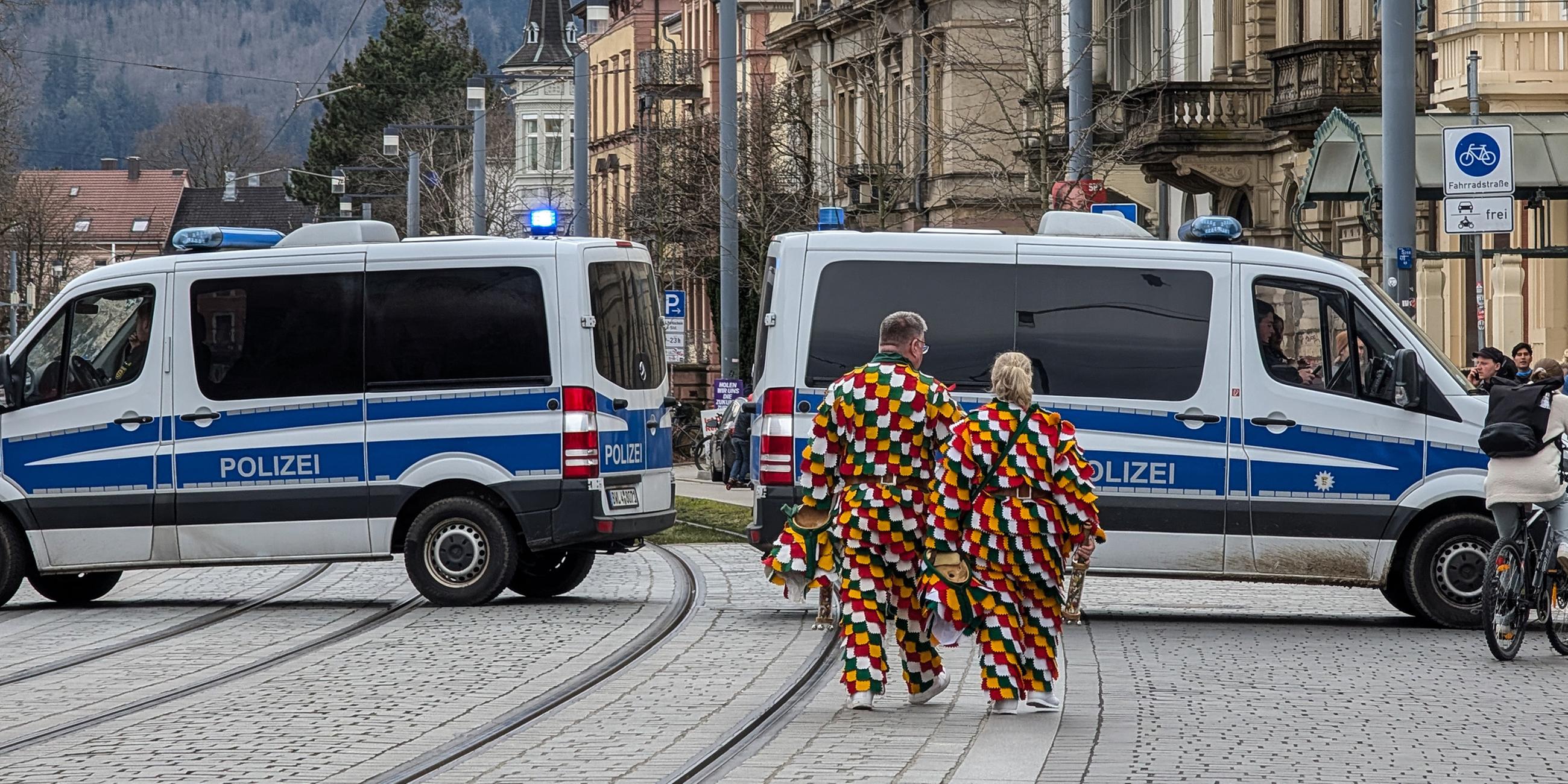 Karnevalisten und Polizeifahrzeuge in Freiburg