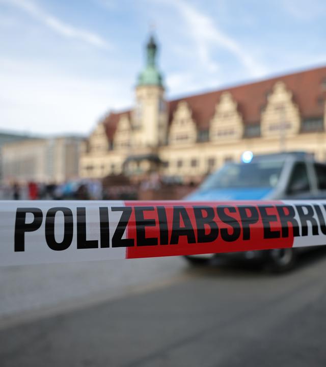 Polizeiabsperrungsband und Polizeiauto in Leipzig.