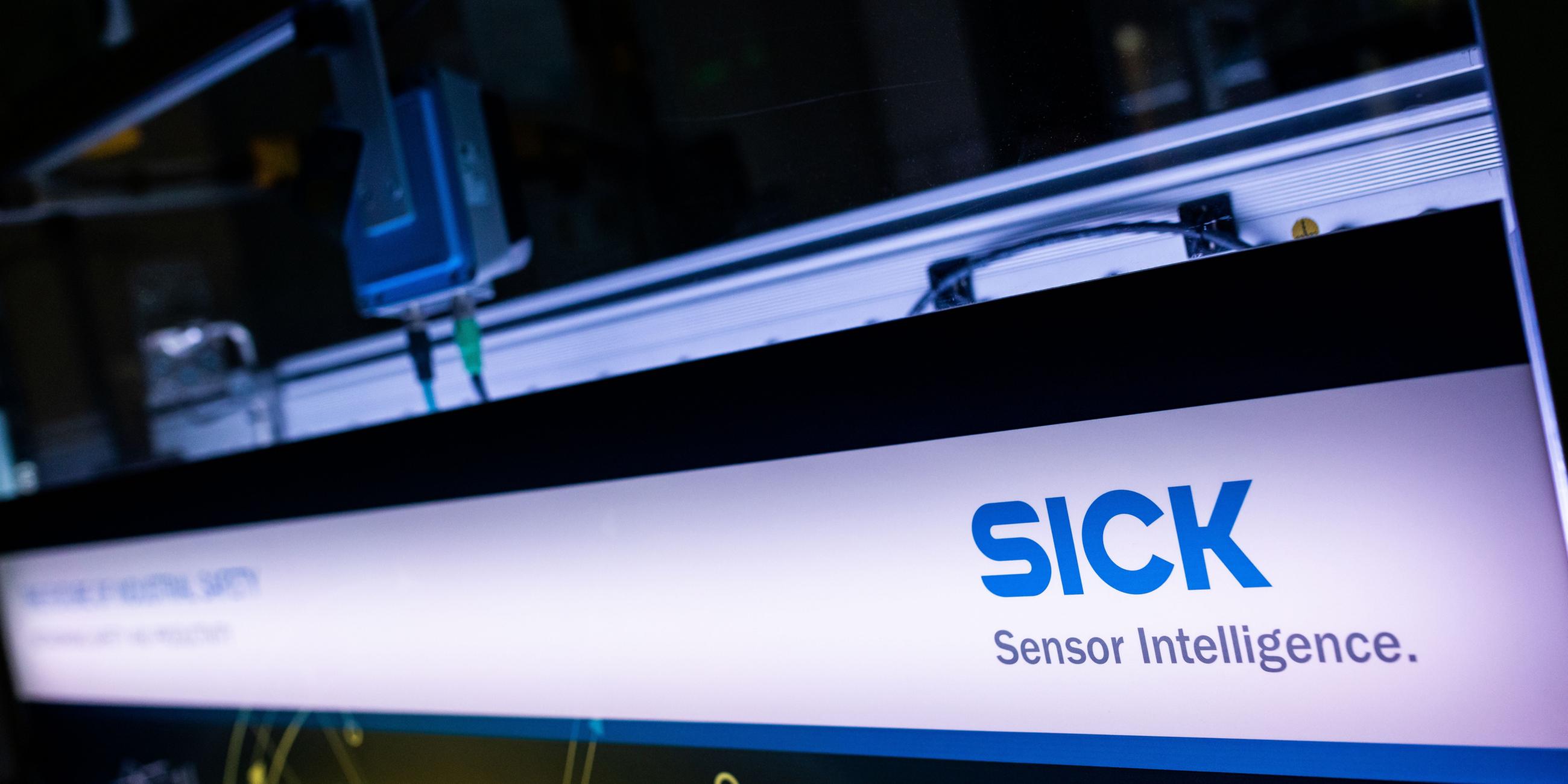 Ein hinterleuchtetes Panel mit dem Logo der Firma steht in einem Showroom der Firma Sick.