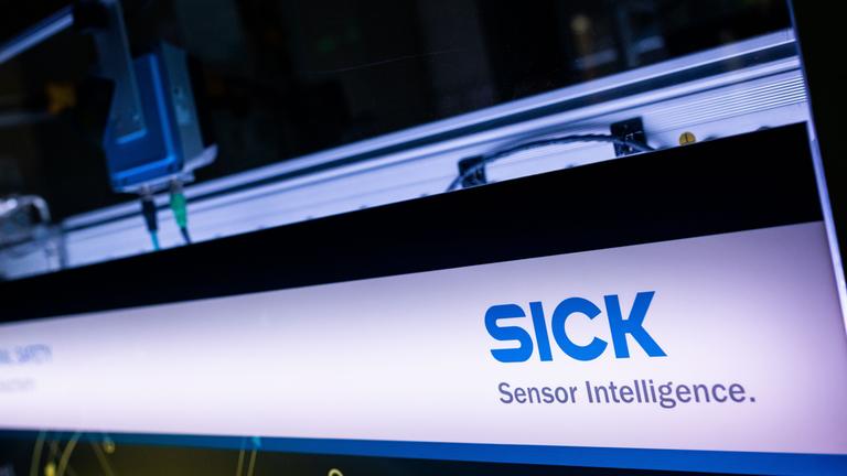 Ein hinterleuchtetes Panel mit dem Logo der Firma steht in einem Showroom der Firma Sick.