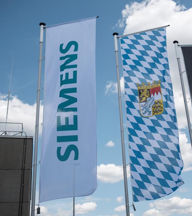 ie Fahnen des Unternehmens Siemens, die Fahne des Freistaats Bayern und die Deutschlandfahne wehen auf dem Gelände der Siemens AG.