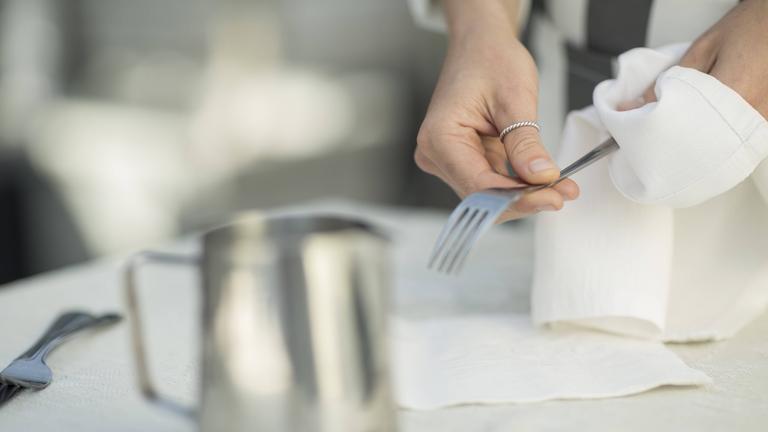 Eine Frau poliert eine Gabel mit einem Stofftuch.