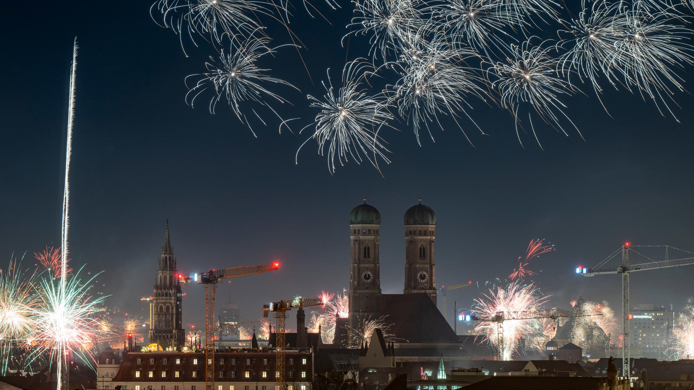 Feuerwerksraketen erleuchten in der Silvesternacht 2026 den Himmel über der Innenstadt von München, in der die beiden Türme der Frauenkirche das Zentrum bilden
