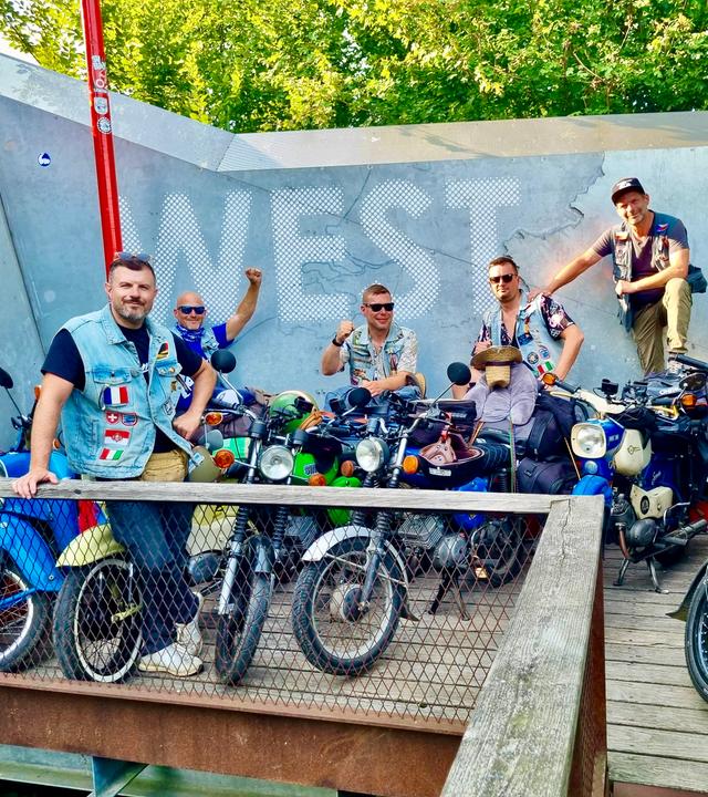 Sechs Männer, im Vordergrund stehen Simson-Mopeds.