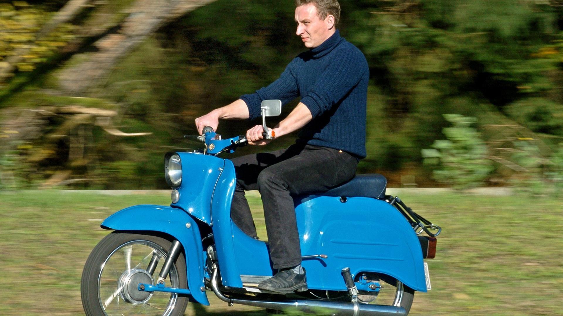 Ein Mann fährt den Motorroller Schwalbe in blau.
