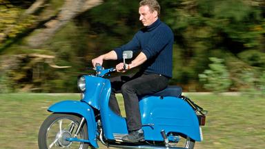 Ein Mann fährt den Motorroller Schwalbe in blau.